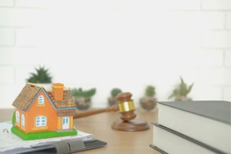 Casa en miniatura junto a mazo legal sobre la mesa, simbolizando disputas legales de propiedad.