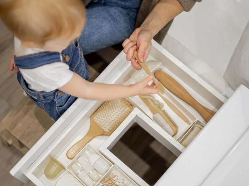 Niño organizando objetos de cuidado personal en un cajón de baño.