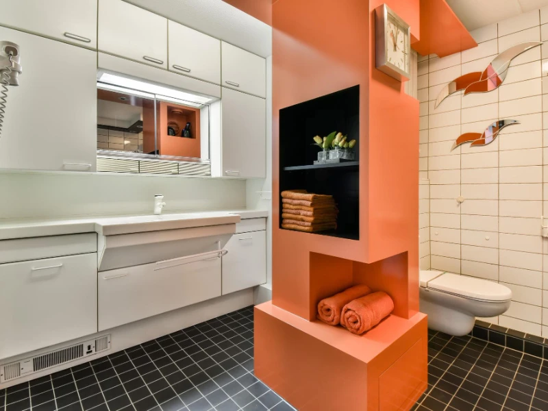 Baño funcional con toallas naranjas y decoración en tonos cálidos.
