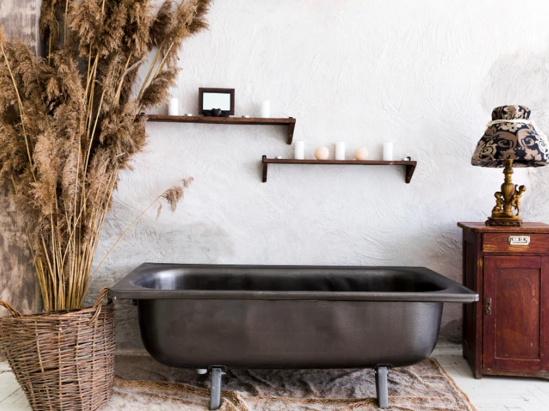 Baño decorado con elementos retro, como una tina metálica y muebles antiguos.