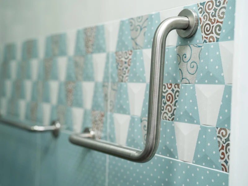 Baño moderno con azulejos hidráulicos y barra de soporte metálica.