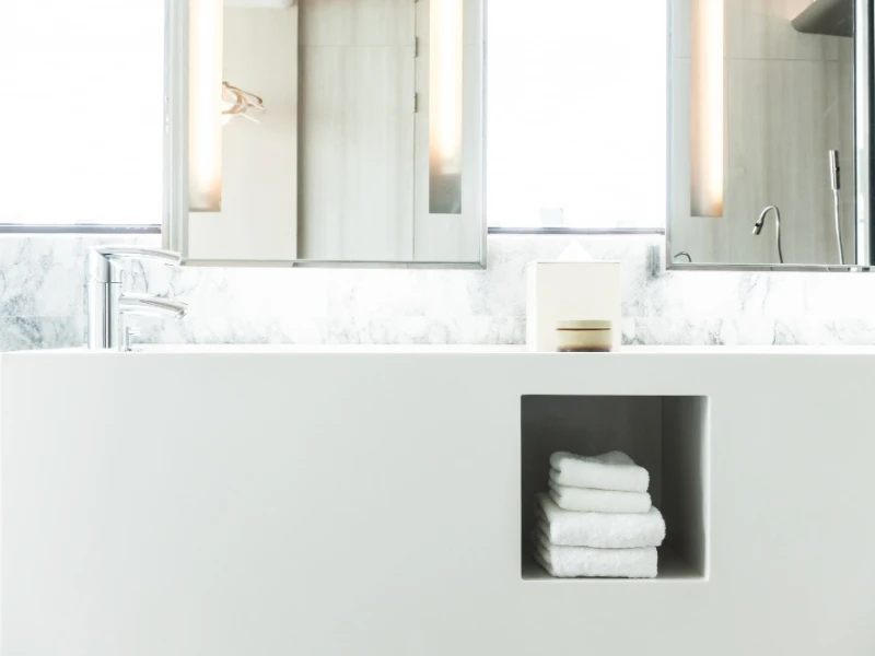 Baño minimalista con lavamanos y toallas en un diseño blanco.
