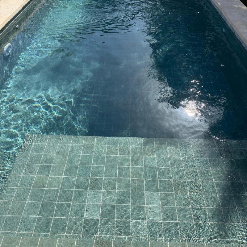 Interior de piscina con agua y revestimiento cerámico verde en Trébaluger.