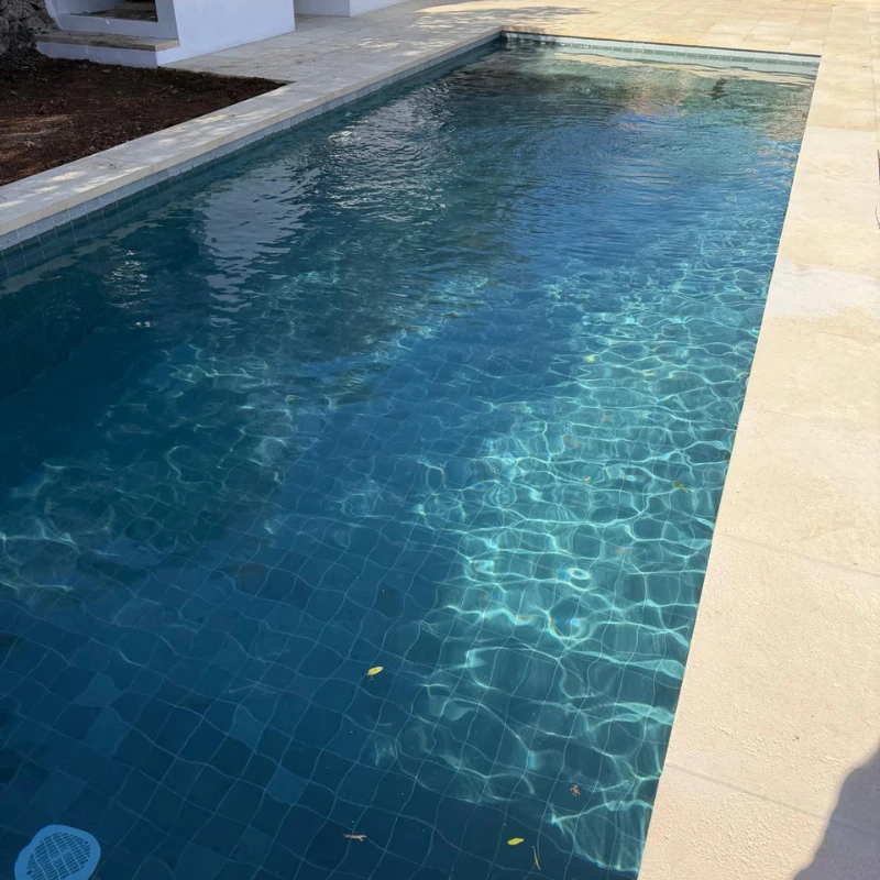 Piscina rectangular acabada con agua cristalina y borde de piedra en Trébaluger.